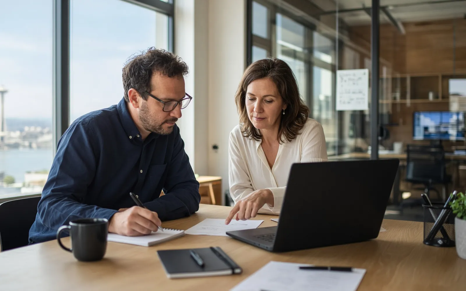 Property management and IT colleagues reviewing work together at a shared desk
